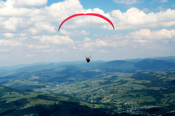 Paraglider flying over summer mountains