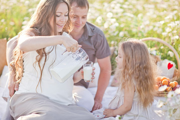 happy little girl drinking milk in the camomile field. picnic