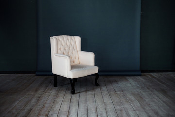 One classic armchair against a dark blue wall and floor. Copy