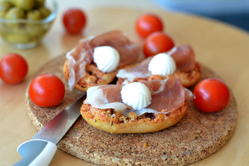 Bruschetta with oregano, prosciutto and mozzarella on a wooden table