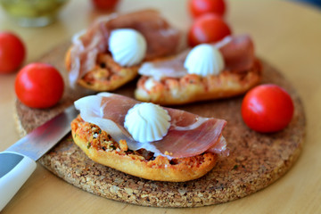 Italian Bruschetta With Mozzarella And Prosciutto On A Wooden Table