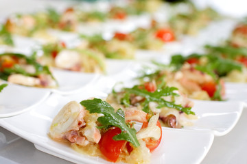 Swedish table appetizers: tomatoes, cheese, arugula, octopus, on