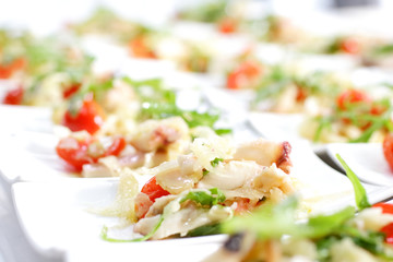 Swedish table appetizers: tomatoes, cheese, arugula, octopus, on