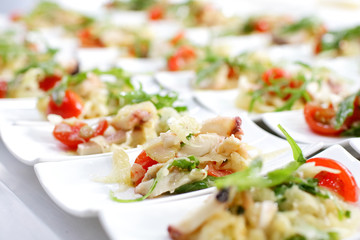 Swedish table appetizers: tomatoes, cheese, arugula, octopus, on