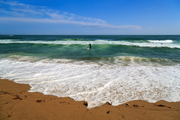 Fototapeta na wymiar Surfer in the Mediterranean Sea near the city beach. Barcelona, Spain