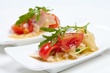 Swedish table appetizers: tomatoes, cheese, arugula, octopus, on