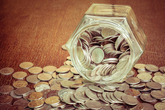 Coins spilling out of a glass bottle with filter effect retro vi