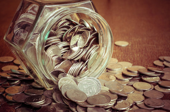 Coins spilling out of a glass bottle with filter effect retro vi