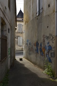 Fototapeta Graffitis sur le mur d'une maison dans un passage étroit 