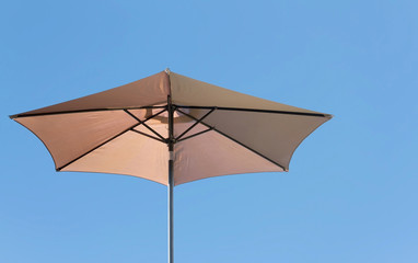 Beige parasol on a clear blue sky