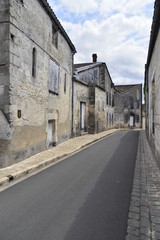 Fototapeta na wymiar L'ombre parallèle au trottoir d'une des rues rénovées du centre historique de Jarnac-sur-Charente