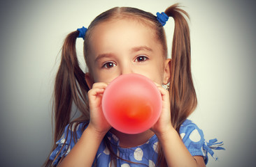 little girl in blue dress inflates red balloon