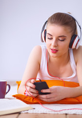 Naklejka premium Young woman lying on floor and listen to music