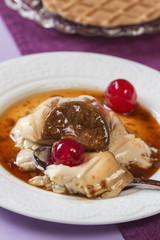 Eating panna cotta with cheries, caramel and wafer