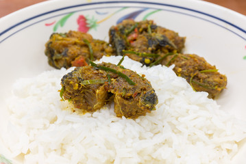 Spicy cat fish with curry herb serve with rice focus at center.