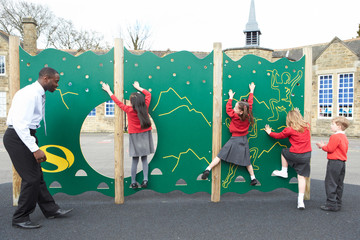 Children On Climbing Wall In School Playground At Breaktime