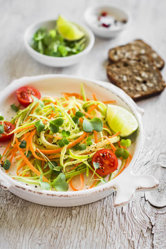 fresh salad with zucchini and carrots in a light vintage plate on a light wooden background