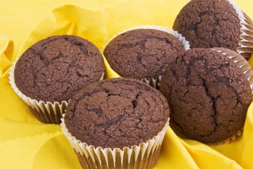 five chocolate cupcakes without icing on a yellow napkin