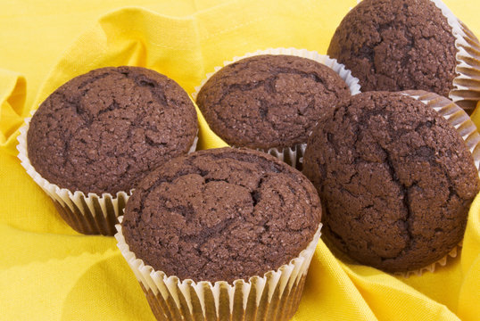 Five Chocolate Cupcakes Without Icing On A Yellow Napkin