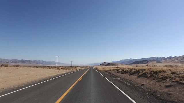 Straight highway in sierra nevada with nobody and a clear blue sky, usa