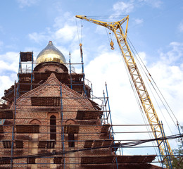 Big yellow tower crane on russian red brick church construction process