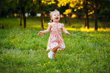 Happy cute little girl running on the grass in the park. Happine