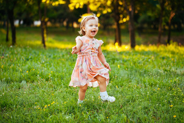 Happy cute little girl running on the grass in the park. Happine