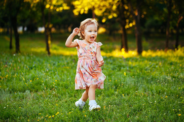 Happy cute little girl running on the grass in the park. Happine