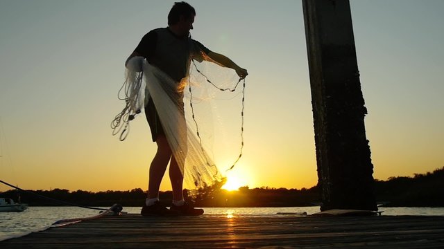 Man casting a shrimping net at sunrise sunset super slow motion video clip 
