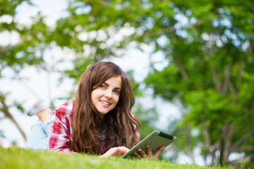 Obraz premium Young woman with digital tablet on the grass