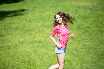 Naklejka na ściany i meble Beautiful girl pink T-shirt fun on the grass