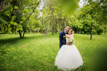 Young lovely and cheerfull wedding couple walking at the park