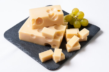 Queso emmental cortado y uvas sobre una tabla de pizarra