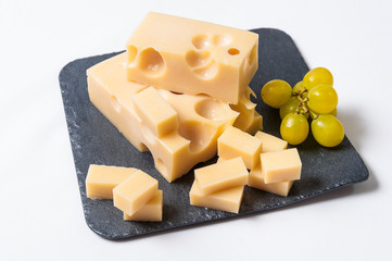 Queso emmental cortado y uvas sobre una tabla de pizarra