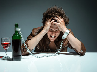 Man in handcuffs interconnected with a bottle of alcohol