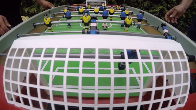 Friends playing table soccer outdoor camera mounted at the football goal