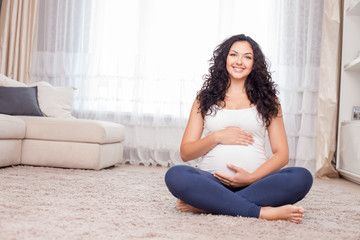 Pregnant healthy woman is relaxing on flooring