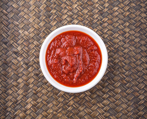 Fresh pureed tomato in white bowl over wicker background