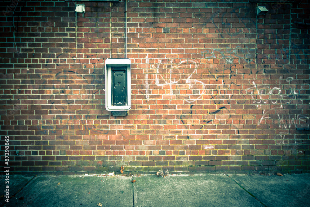 Wall mural grungy urban background of a brick wall with an old out of service payphone on it