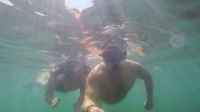 Couple exploring underwater terrain with snorkeling gear swimming in sea