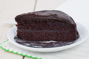 Dark chocolate cake on white plate on wooden table