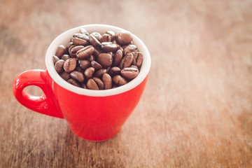 Red coffee cup with coffee beans on wooden table