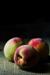 Juicy peaches in old wooden tray on black background