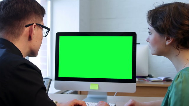 Two businessmen talking and looking at the computer display. Man and woman are talking business before the monitor. Chroma key screen
