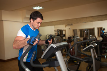 Naklejka na ściany i meble Man exercising on elliptical machine in gym