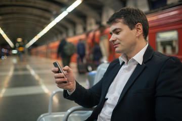 Businessman with smartphone in subway