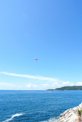 Paragliding above blue sea on a sunny day. Summer seascape. Concept of freedom and adventure.