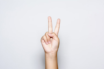 Boy raising two fingers up on hand it is shows peace strength fight or victory symbol and letter V in sign language on white background.
