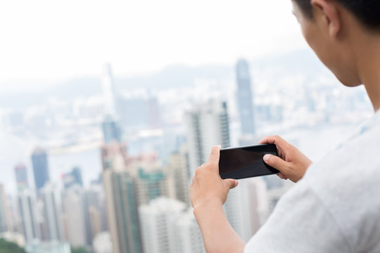 hand holding mobile phone with cityscape as background