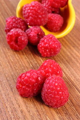Fresh raspberries in bowl on wooden surface, healthy food